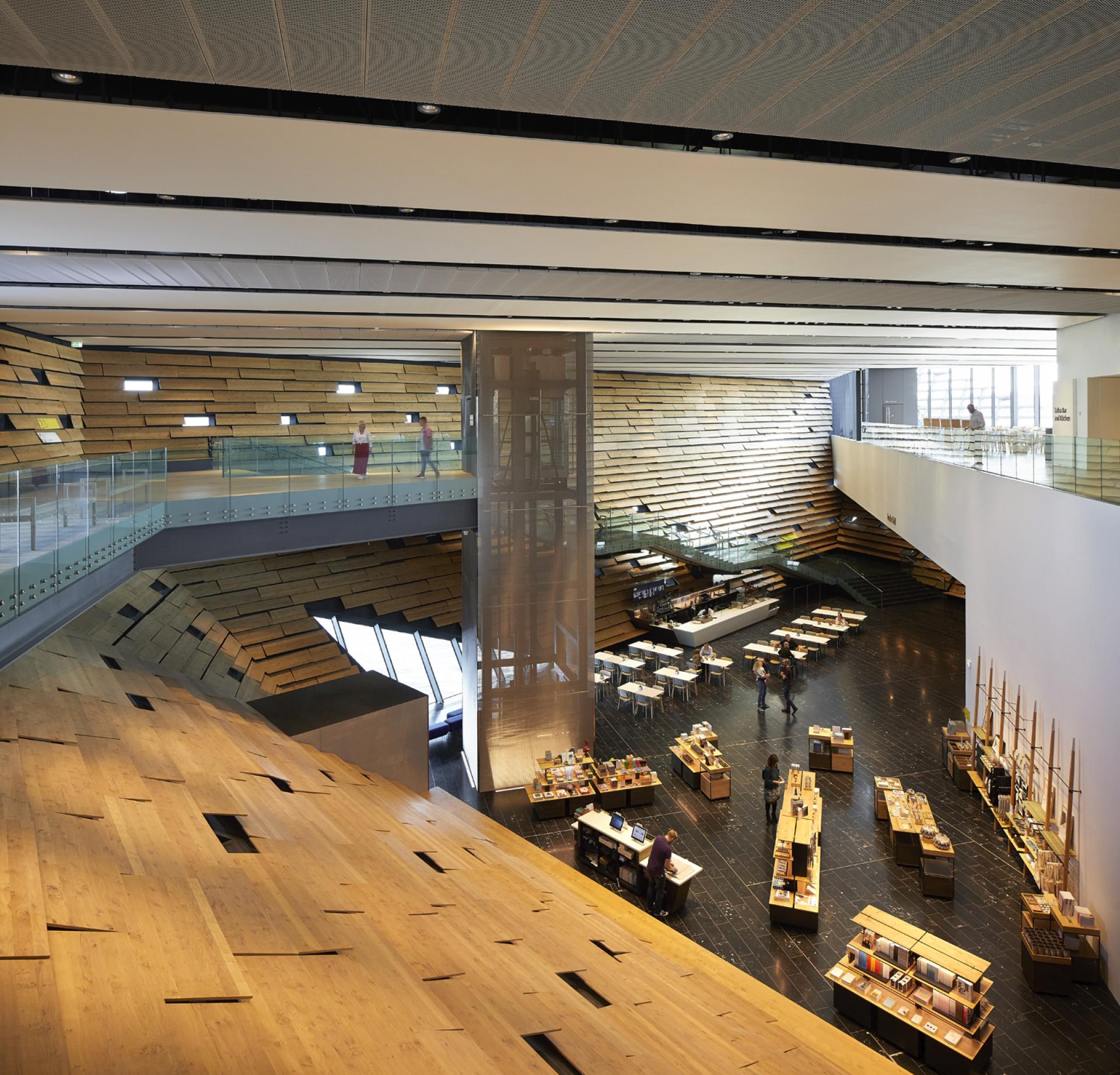 Light-filled interior of V&A Dundee, showcasing wooden design elements by architect Kengo Kuma and a vibrant atmosphere.
