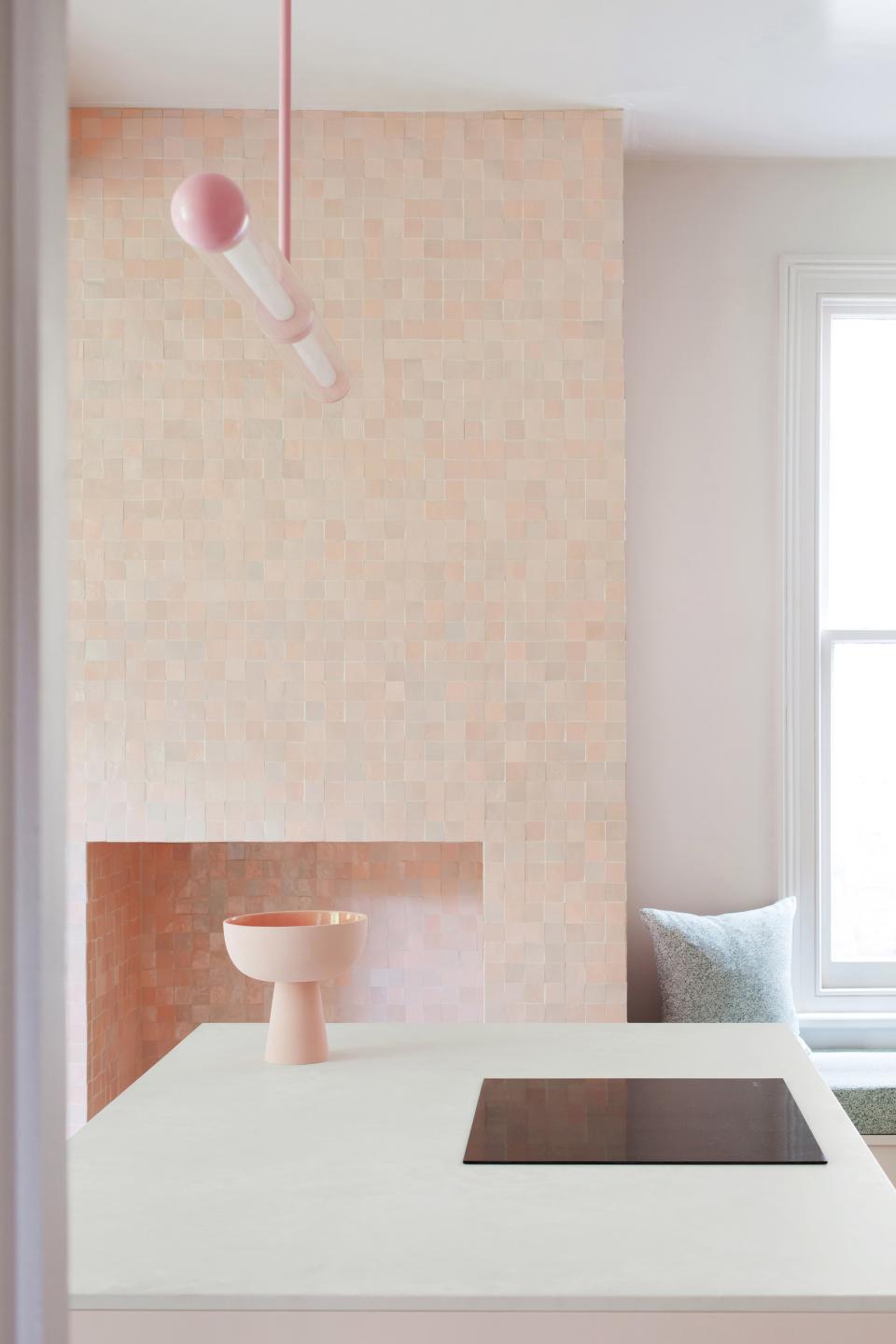 Modern kitchen featuring a pink tiled wall, minimalist countertop, and stylish bowl, highlighting practical design and soft materials.