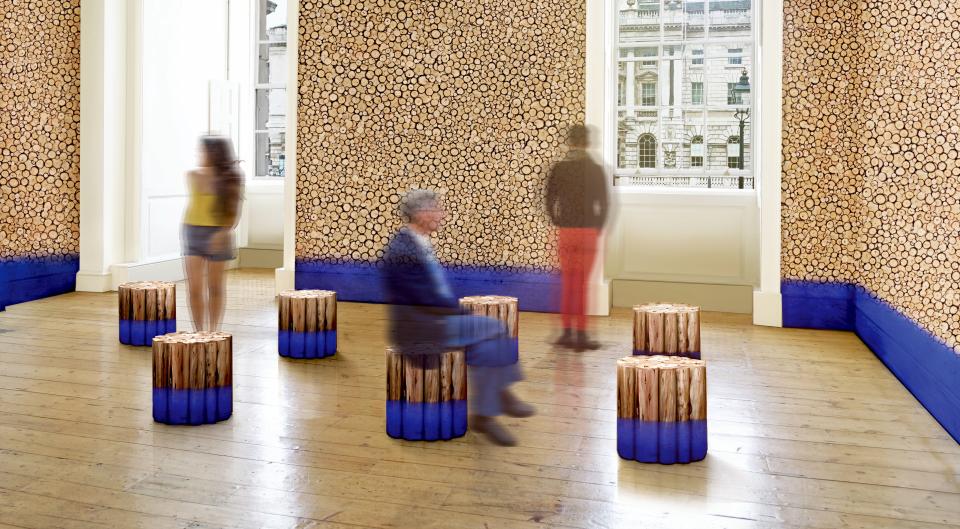 David Elia's installation features wooden stools and a wood-themed wall, representing Brazil's rainforest vulnerability.