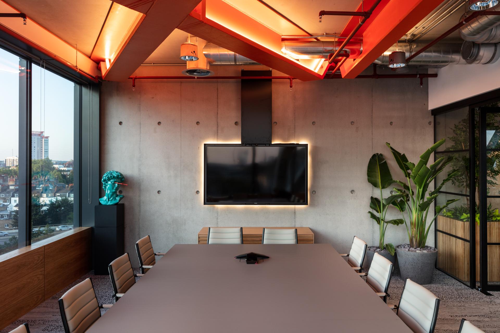 Modern meeting room featuring sleek furniture, large screen, and vibrant design elements for an inspiring workspace.