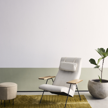Modern interior featuring a textured green rug by FLOOR_STORY, a stylish armchair, and a potted plant.