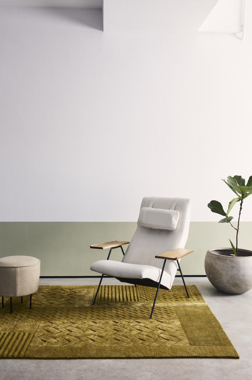 Modern interior featuring a textured green rug by FLOOR_STORY, a stylish armchair, and a potted plant.