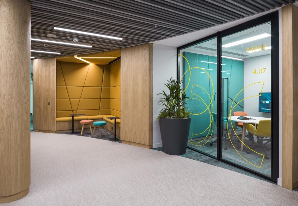 Modern office space featuring WELL certified design elements, including vibrant meeting rooms and comfortable seating areas.