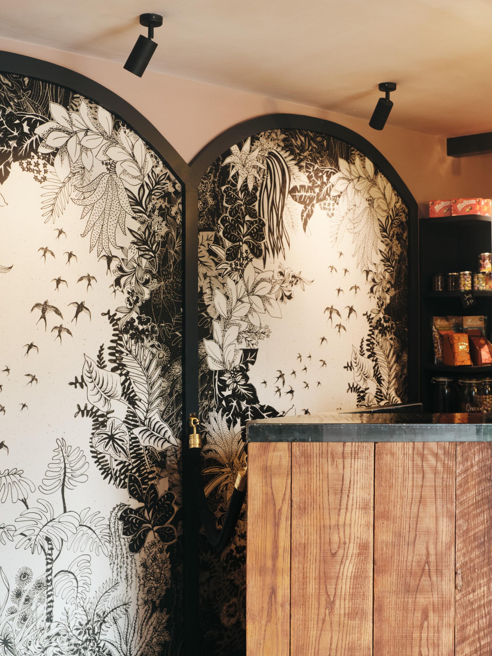 Stylish wooden counter and intricate botanical mural inside The Lexi, London's social enterprise cinema designed by RISE Design Studio.