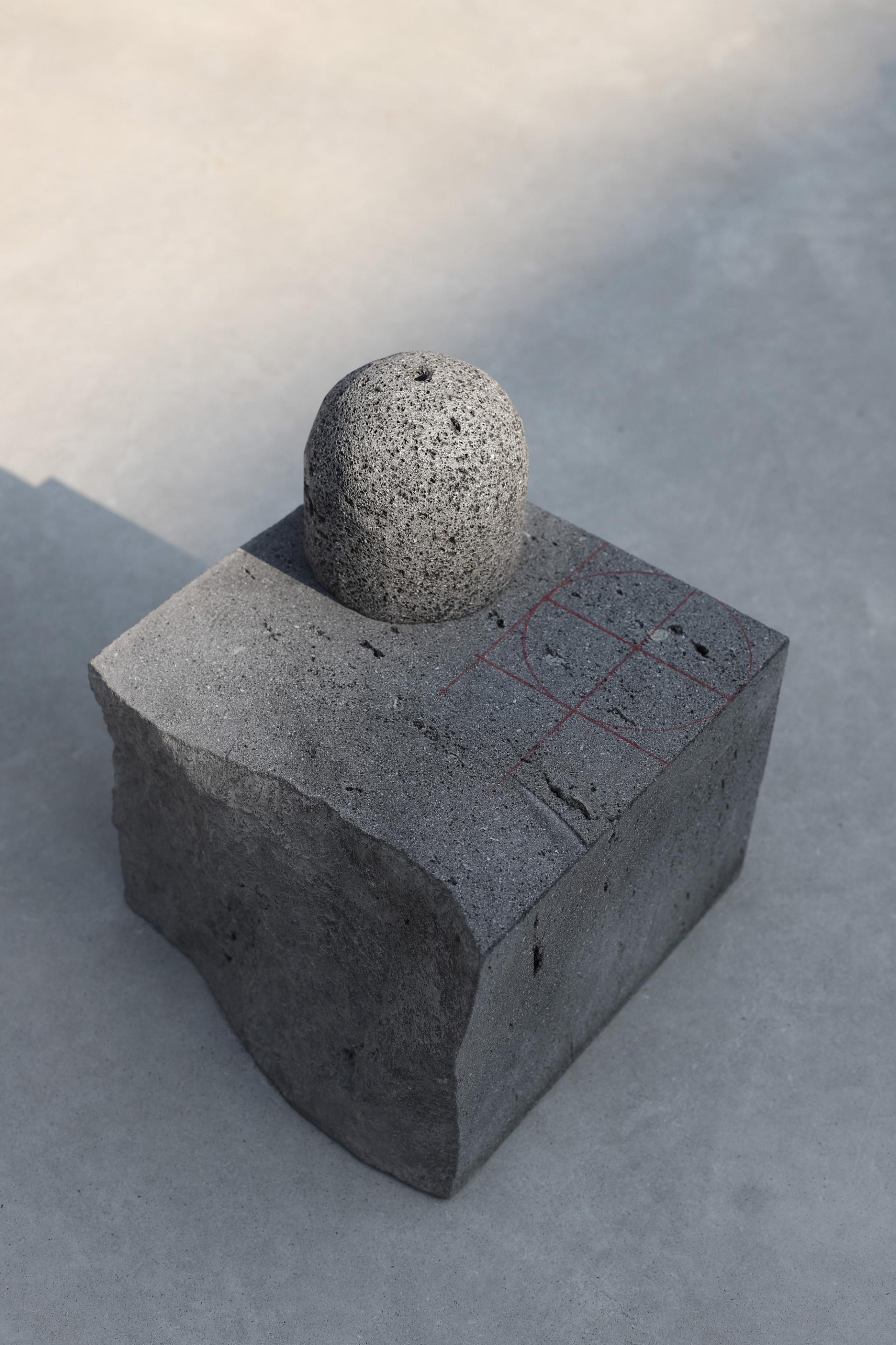 Minimalist stone sculpture featuring a spherical top on a cubic base, showcasing innovative design from the Origo collection.