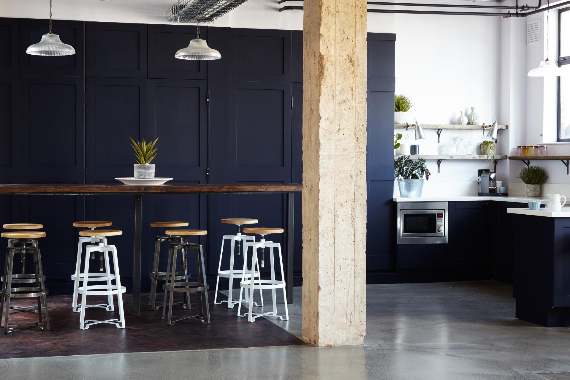 Chic loft-style kitchen with dark cabinets, wooden bar stools, and modern appliances, highlighting Run For The Hills' design transformation.