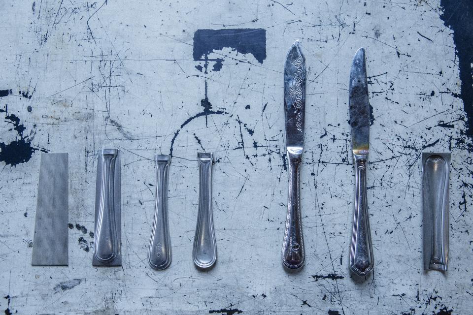 Various metal utensils displayed on a textured surface, showcasing Tsubame-Sanjo's metal craftsmanship at Japan House London.