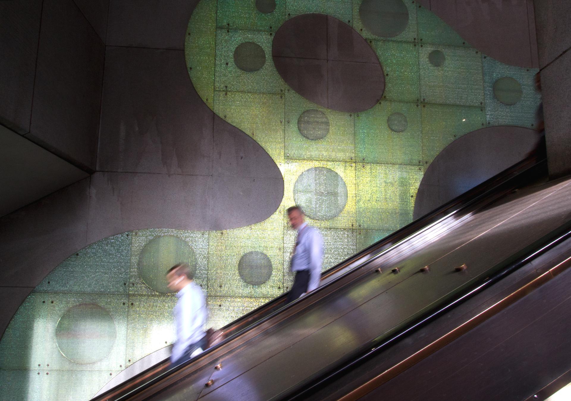 Dynamic light reflections on architectural glass at an escalator, illustrating innovation and sustainability in design.