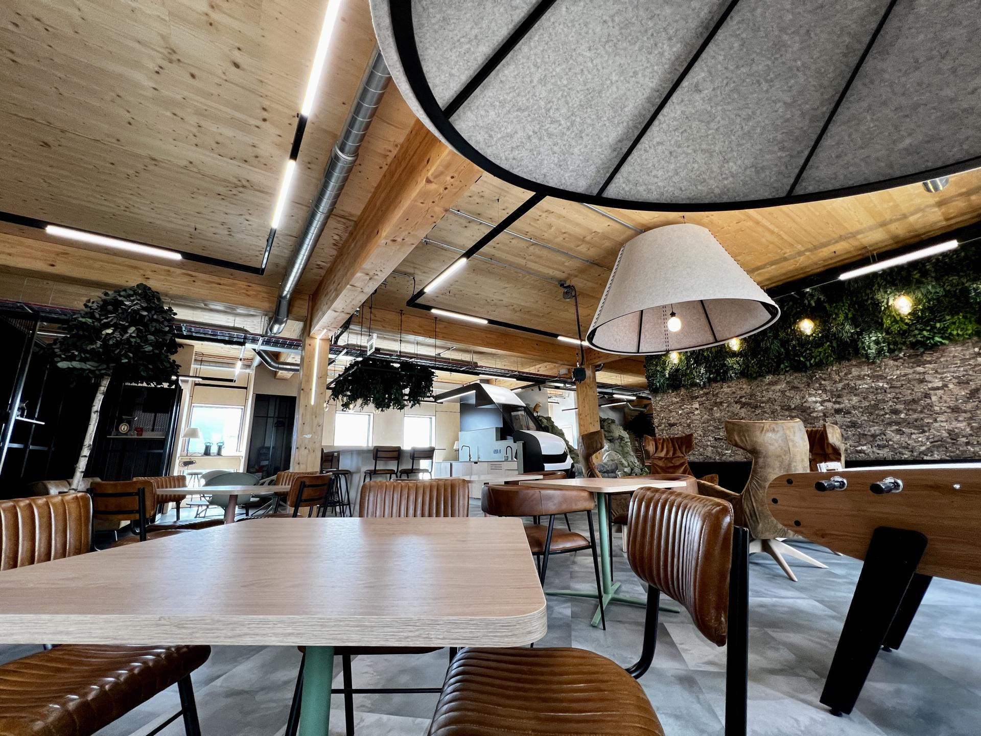 Modern workspace interior featuring wooden beams, stylish furniture, and greenery, highlighting Leeds' first net zero carbon design.