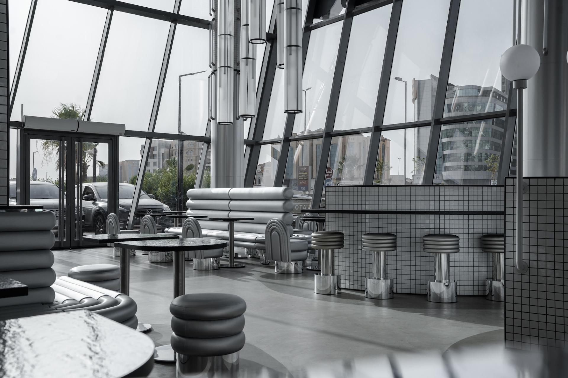 Contemporary interior design of MO bakehouse and espresso bar featuring sleek seating and large glass windows.