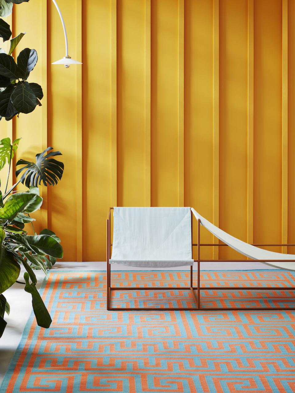 Mediterranean-inspired rug by Adam Nathaniel Furman displayed in a vibrant setting with modern furniture and plants.