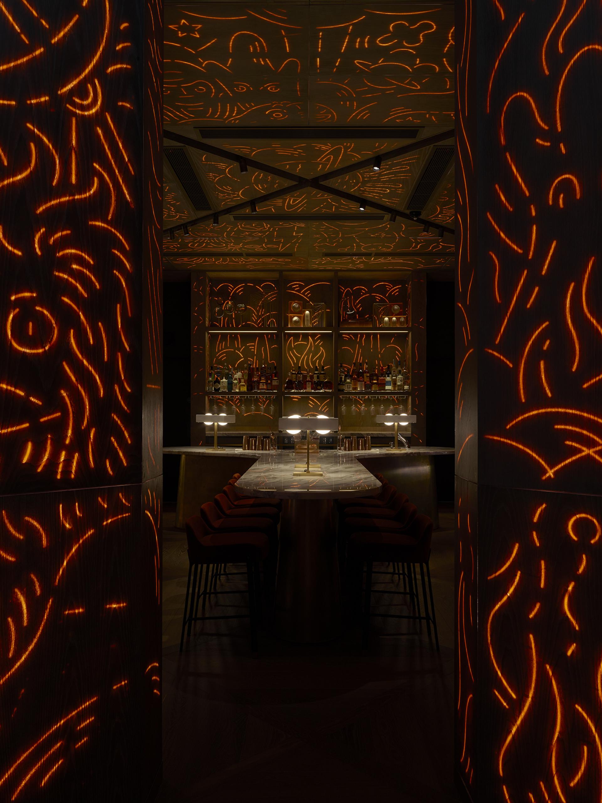 The interior design of a Leicester Square hotel features theatrical lighting and artistic wall patterns, creating an immersive atmosphere.