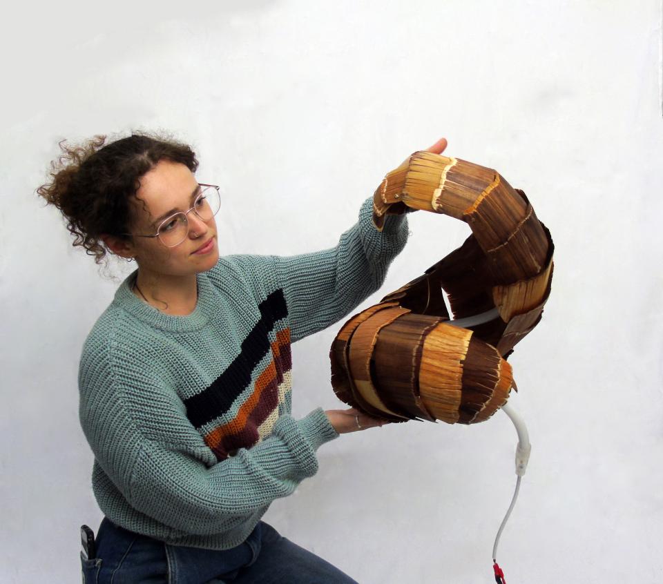 A designer showcases a unique, handmade lamp crafted from natural materials at the Surface Design Show.
