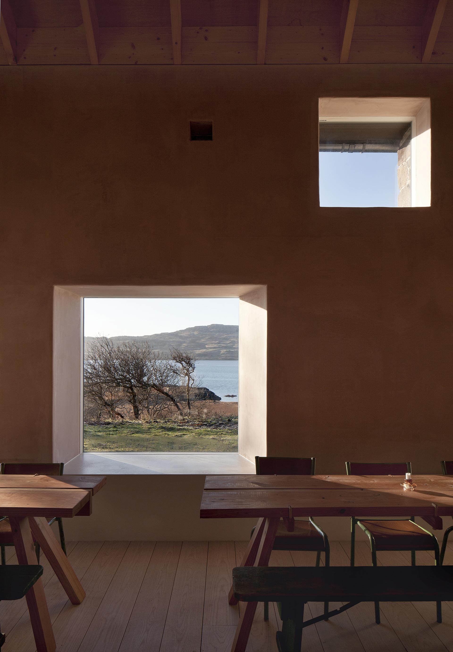 Warm-toned interior view of Croft3, featuring a large window overlooking the Isle of Mull's scenic landscape and water.