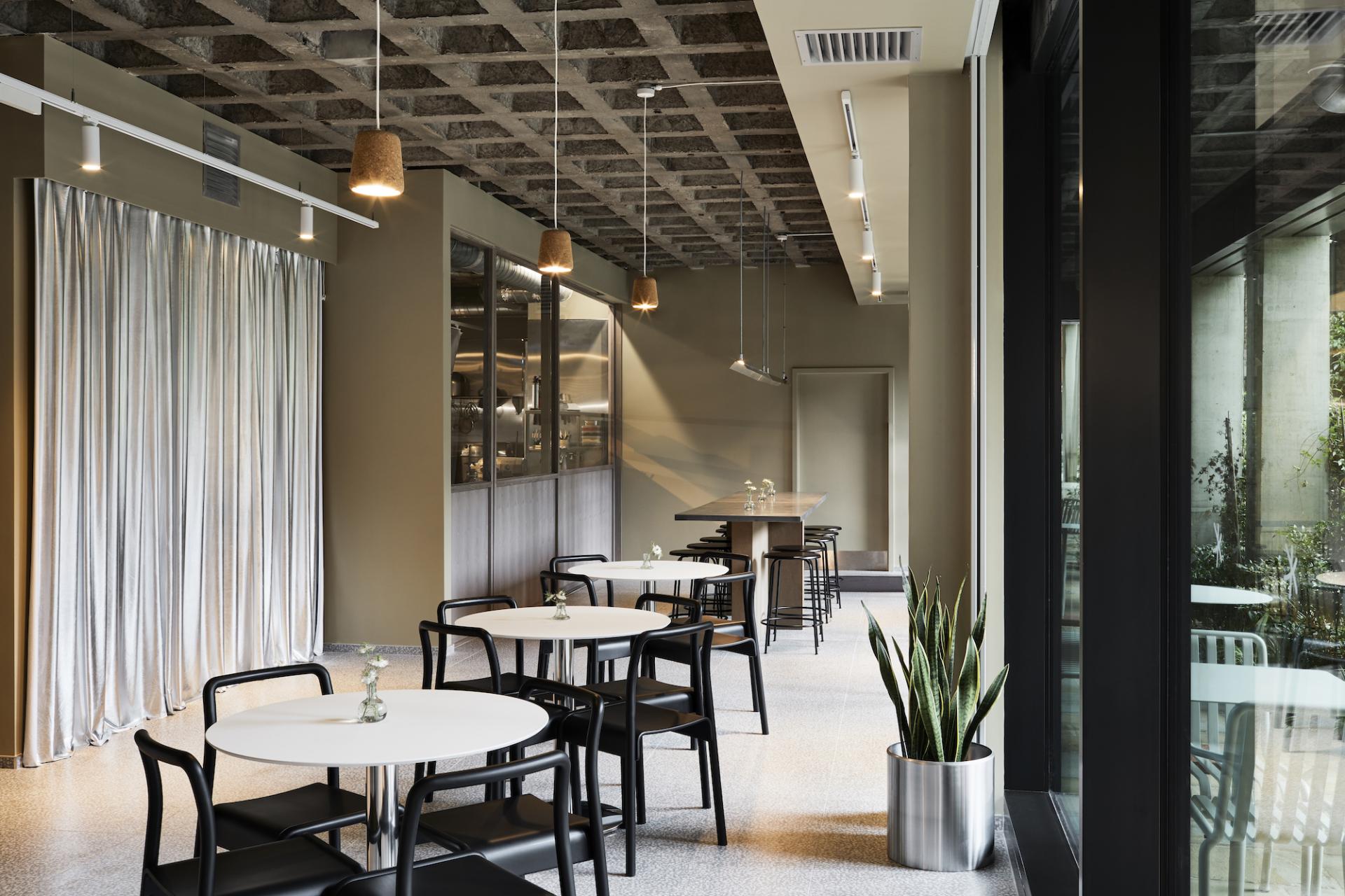 Contemporary patisserie interior at Pollen Bakery featuring stylish tables, plants, and heritage design elements.