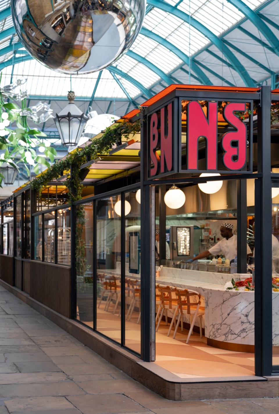 Vibrant entrance of Buns & Buns restaurant in Covent Garden with modern decor and chefs at work.