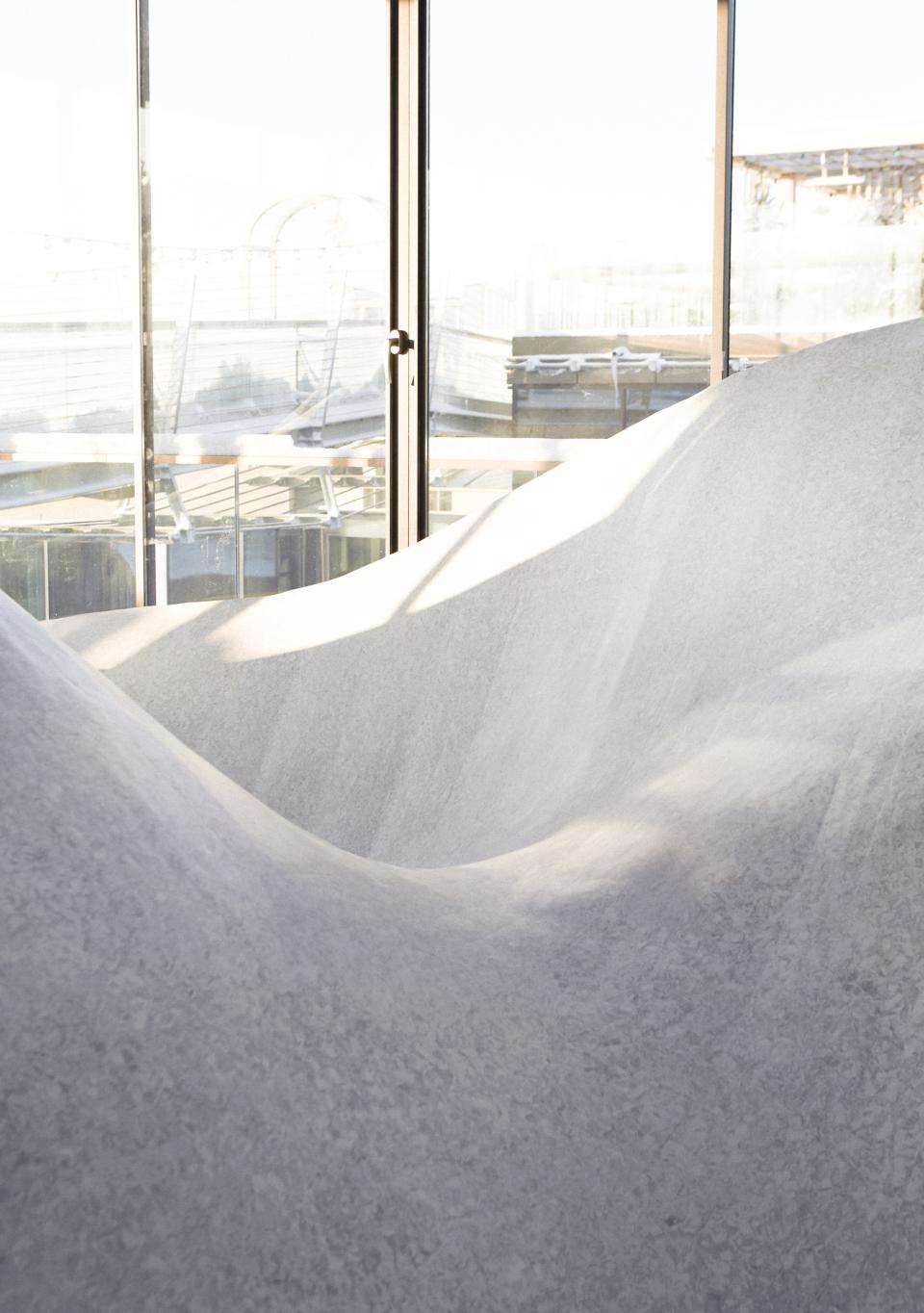 Flowing white shapes resemble winter landscapes, illuminated by natural light, highlighting Tarkett and Note Design Studio’s Snowtopped exhibition.