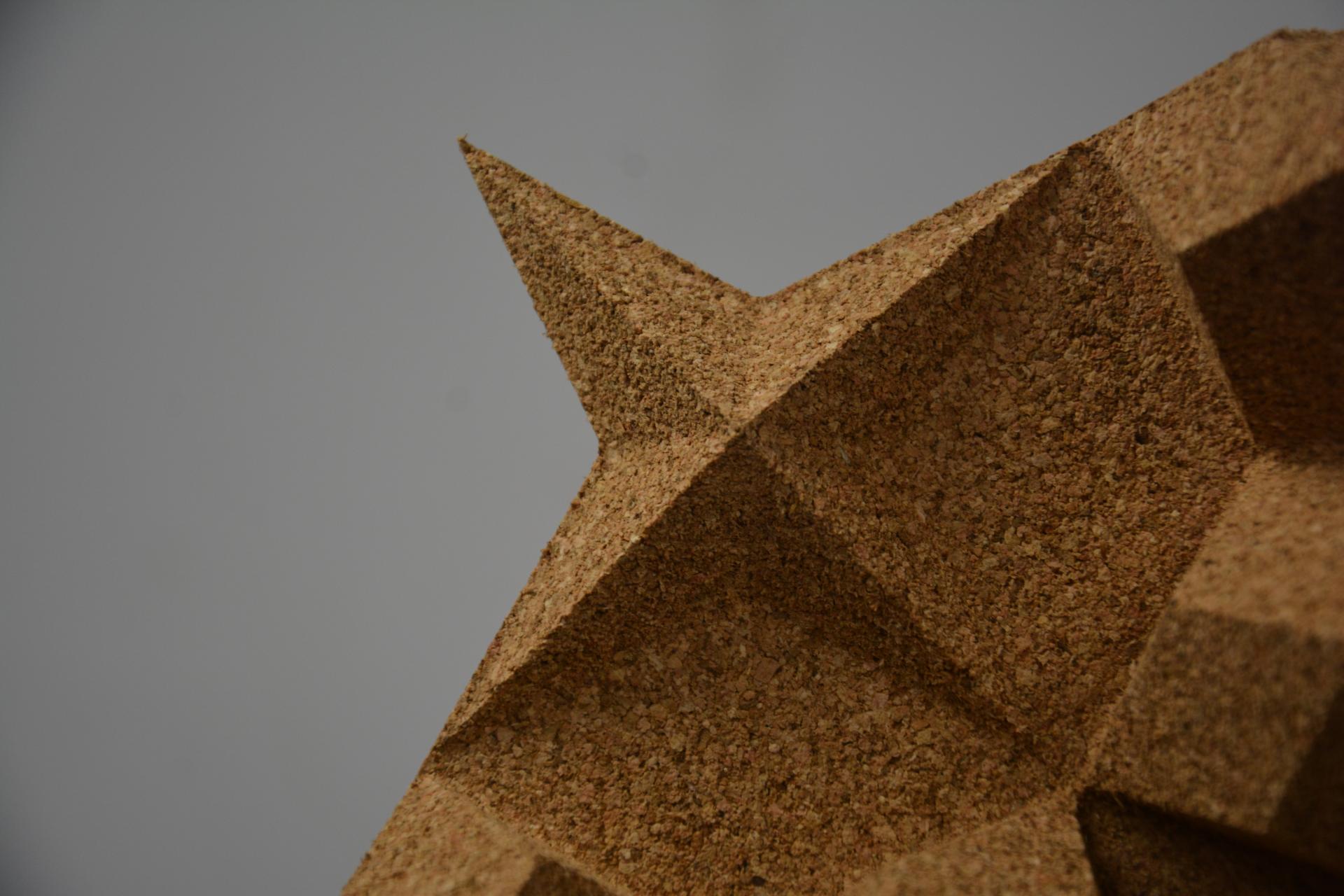 Intricately designed cork sculpture with geometric shapes showcased at New Designers 2024 event, highlighting innovative material use.