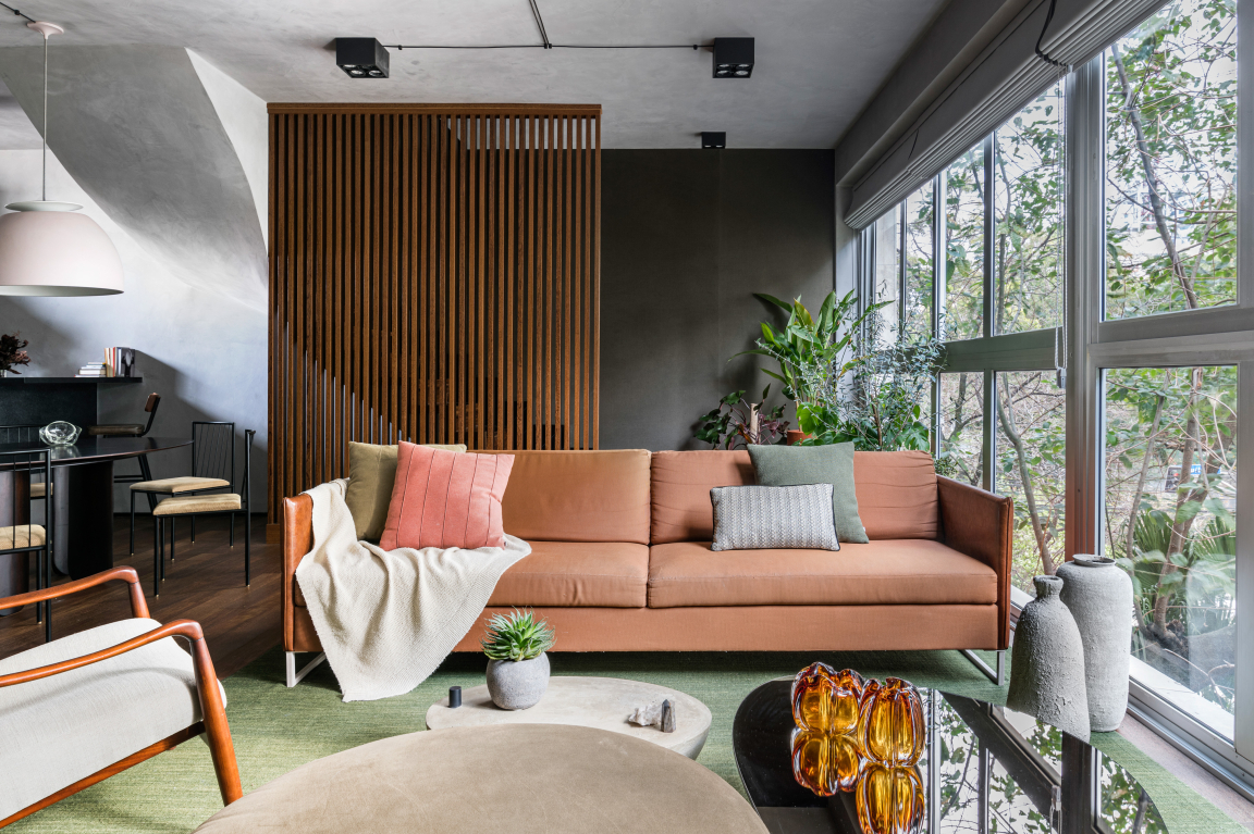 Stylish interior of Apto Paulista showcasing natural light, modern furniture, and lush green plants for a harmonious atmosphere.