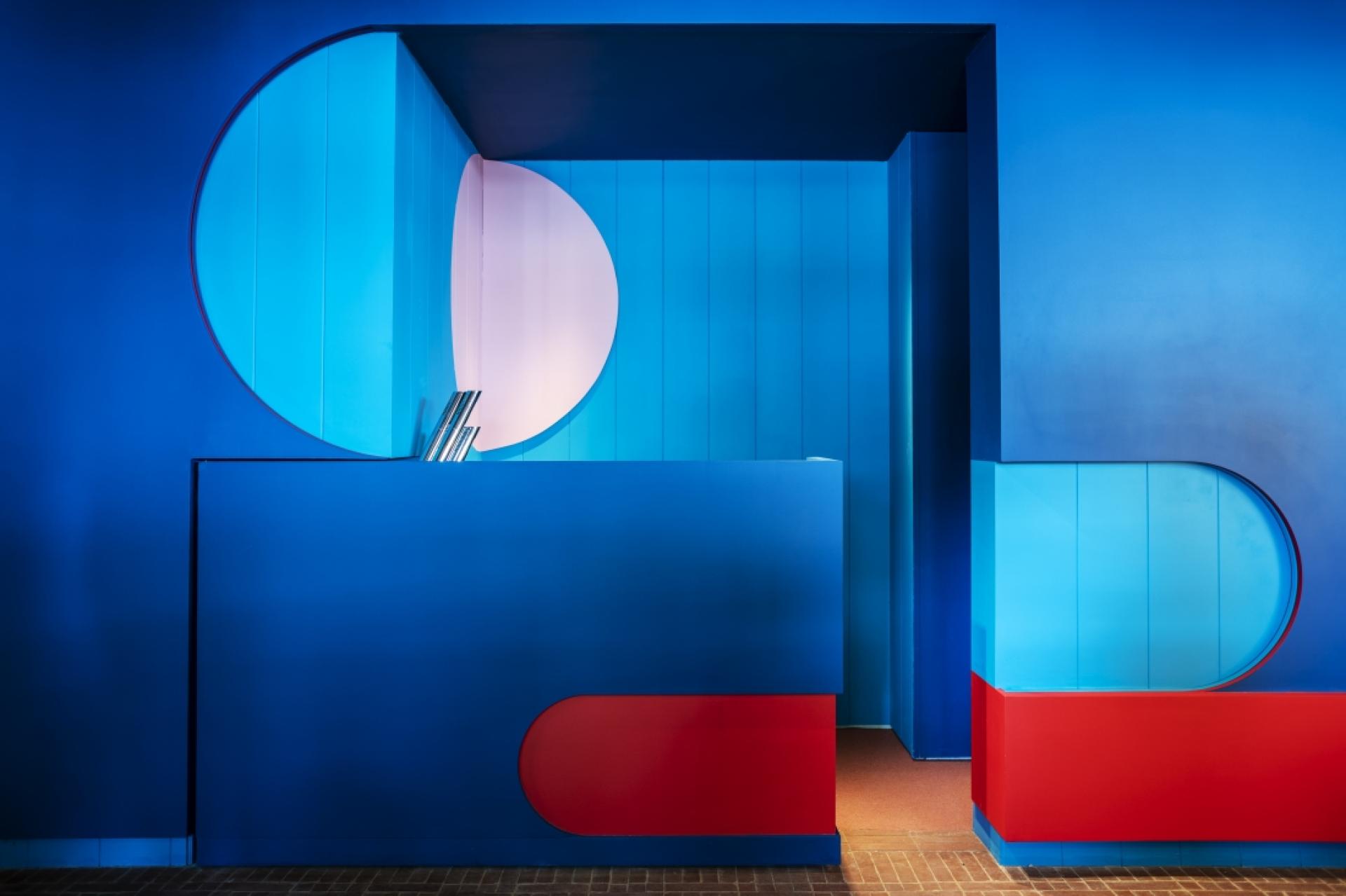 Vibrant blue and red interior design featuring geometric shapes, showcasing modern aesthetics in 2019 architecture trends.