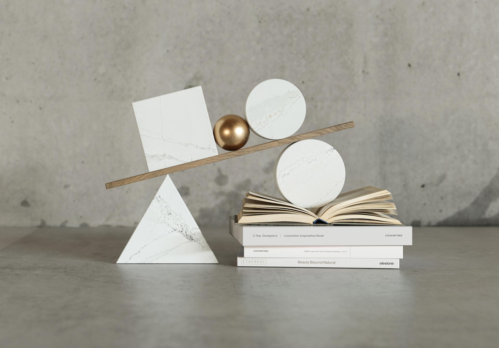 Contemporary display featuring Silestone® Ethereal surfaces, geometric shapes, a golden sphere, and architecture-inspired books.