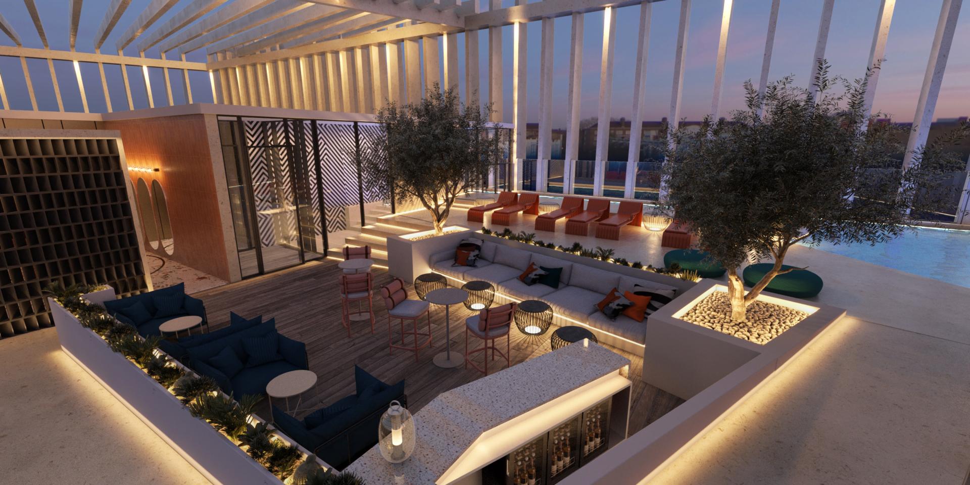 Stylish rooftop lounge area of Tribe hotel featuring modern furnishings, greenery, and a pool with ocean views.