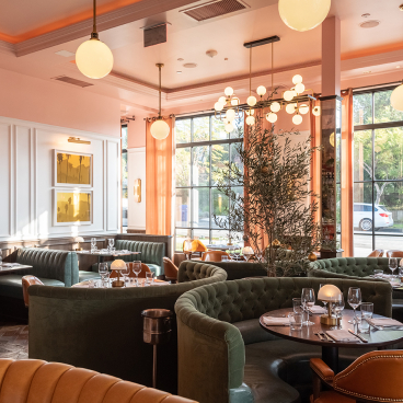 Elegant brasserie interior featuring plush seating, artistic decor, and large windows for natural light, designed by Fettle.