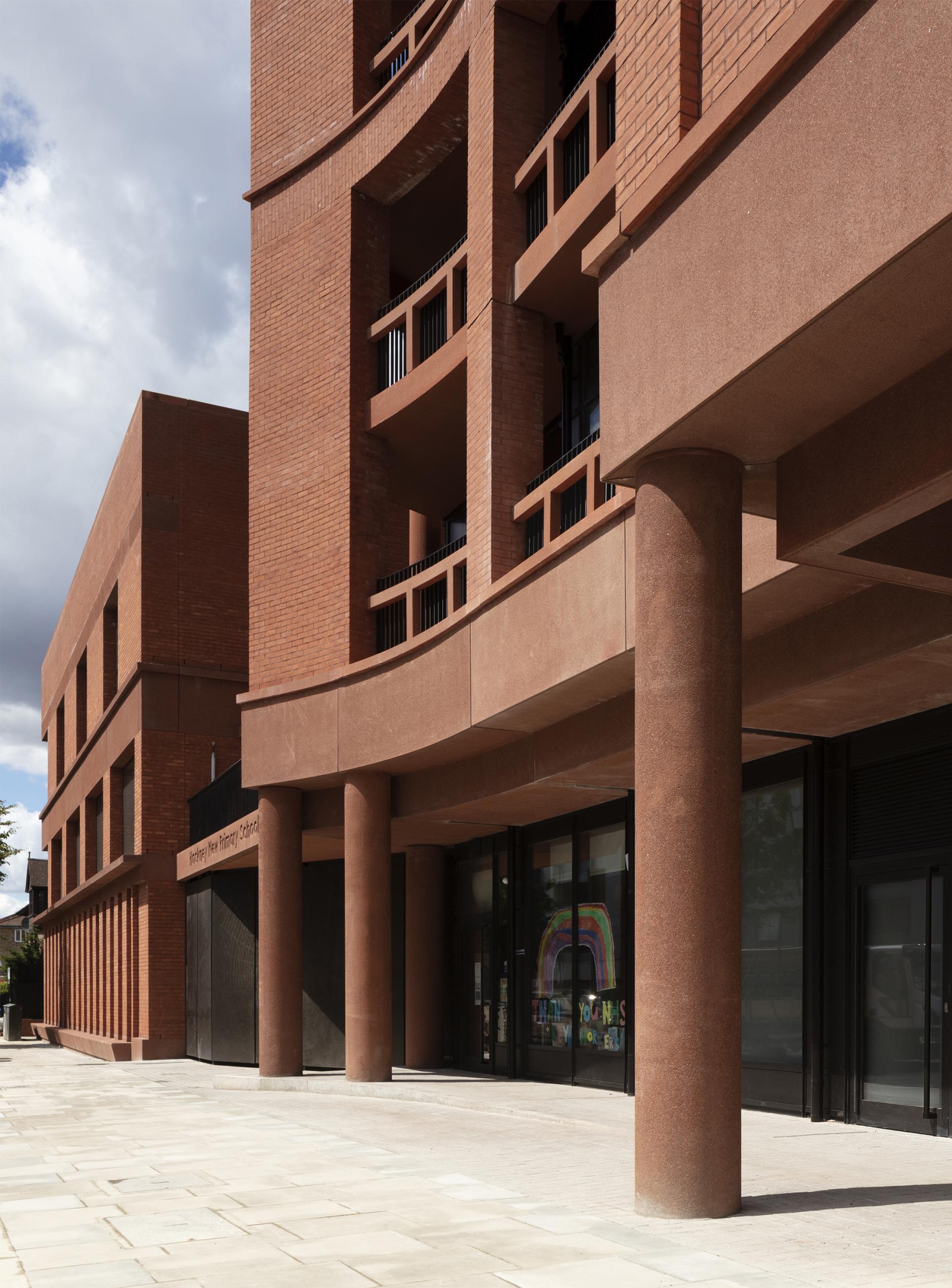 Modern red brick school building exterior showcasing curved architecture and prominent columns. RIBA 2022 Stirling Prize candidate.