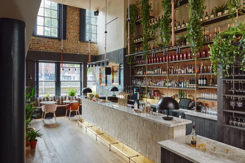 Stylish bar area at Zanzibar Locke aparthotel, featuring retro decor, greenery, and an extensive selection of drinks.