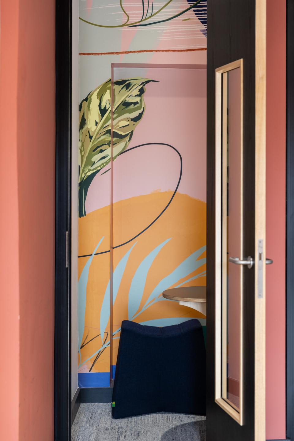 Vibrant mural with tropical patterns and a cozy seating area in a co-working space designed by Sheila Bird Studio.