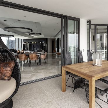 Stylish outdoor dining area featuring a wooden table and modern chairs, reflecting Elliot James' edgy apartment design.