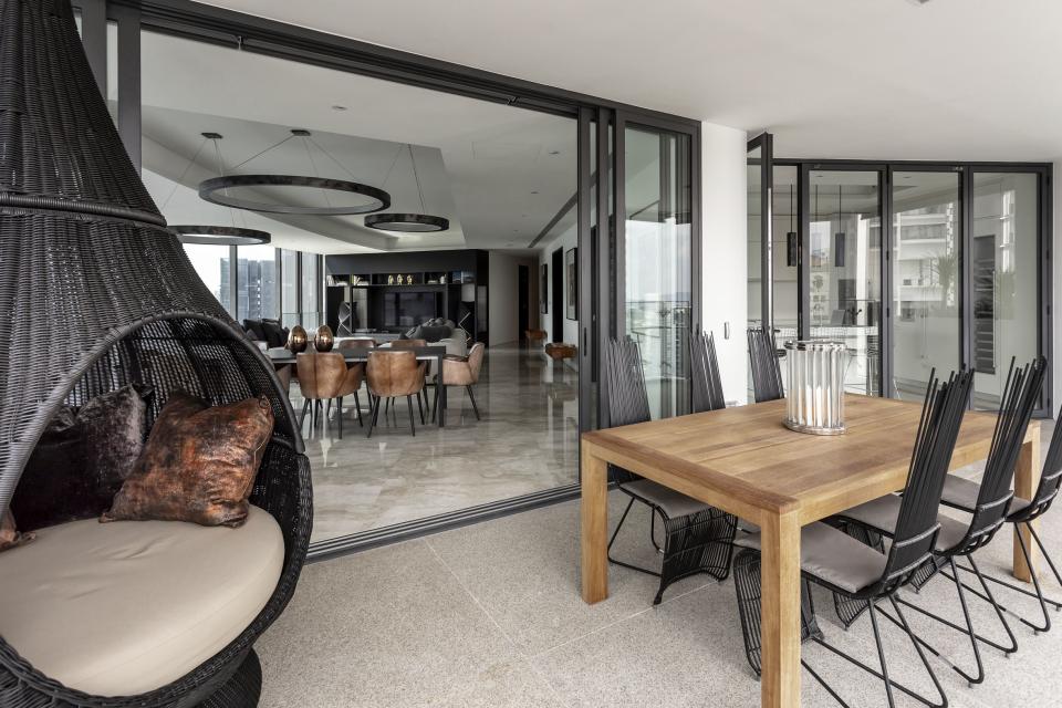 Stylish outdoor dining area featuring a wooden table and modern chairs, reflecting Elliot James' edgy apartment design.