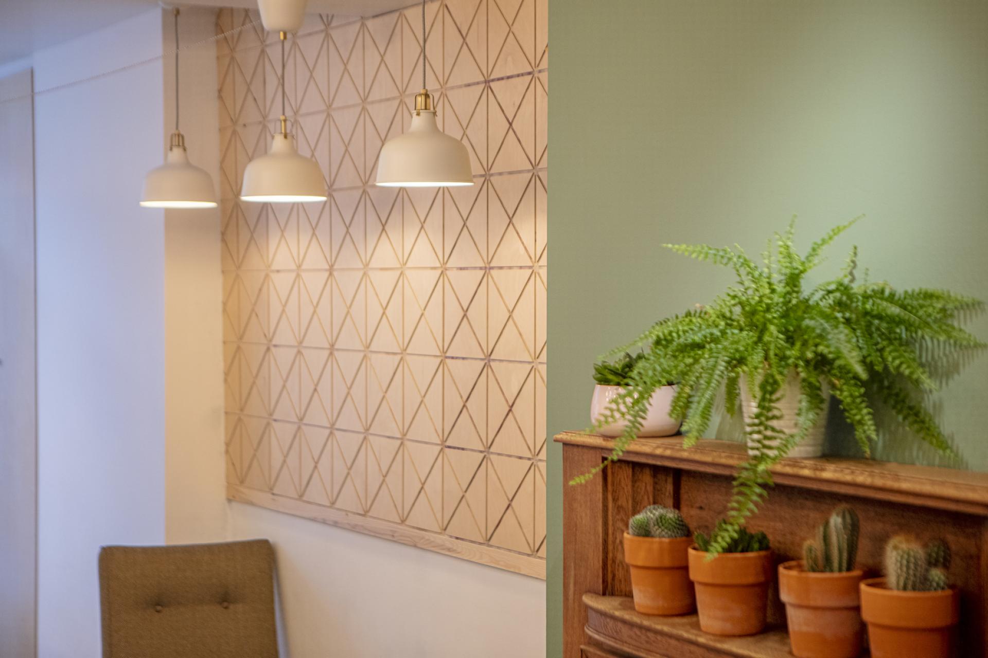 Stylish interior of Brew 204 featuring pendant lights, textured wall, plants, and wooden furniture designed by Liqui Group.