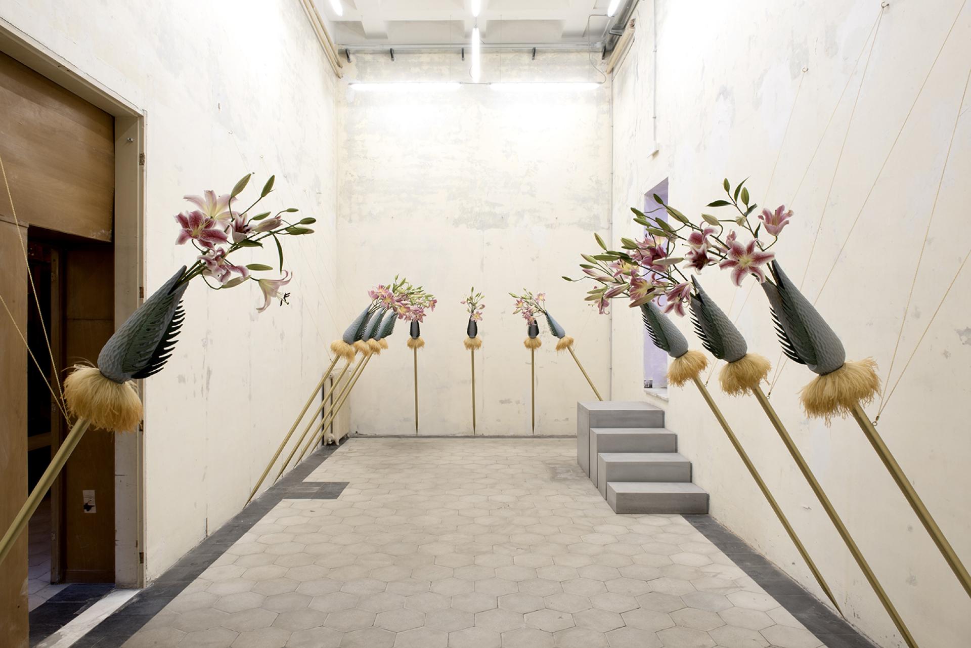 Inside Palazzo Brancaccio, an art installation features floral sculptures on poles, enhancing the contemporary ambiance.