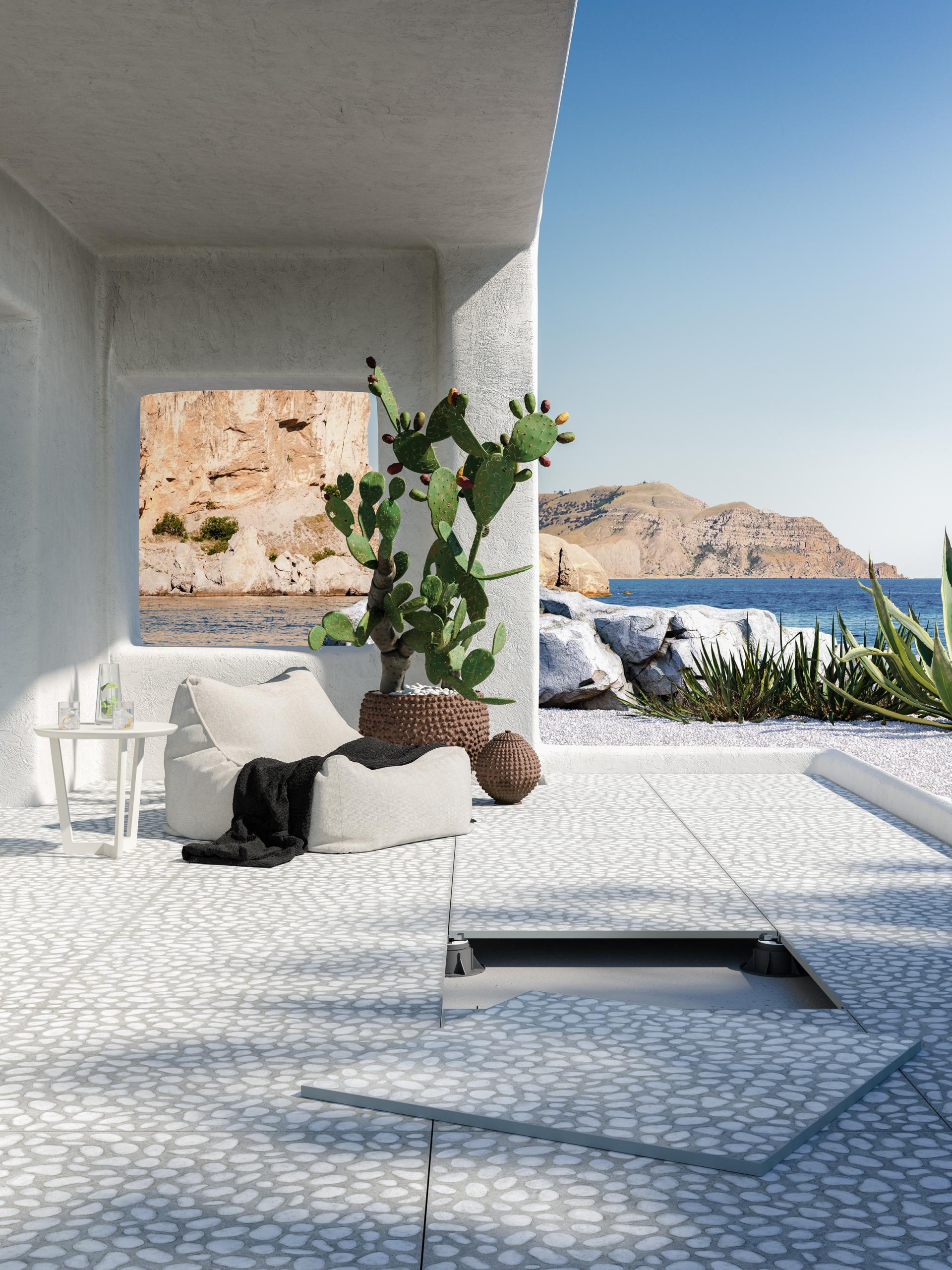 Contemporary outdoor lounge featuring geometric tile flooring, a cactus centerpiece, and scenic coastal views at CERSAIE 2019.