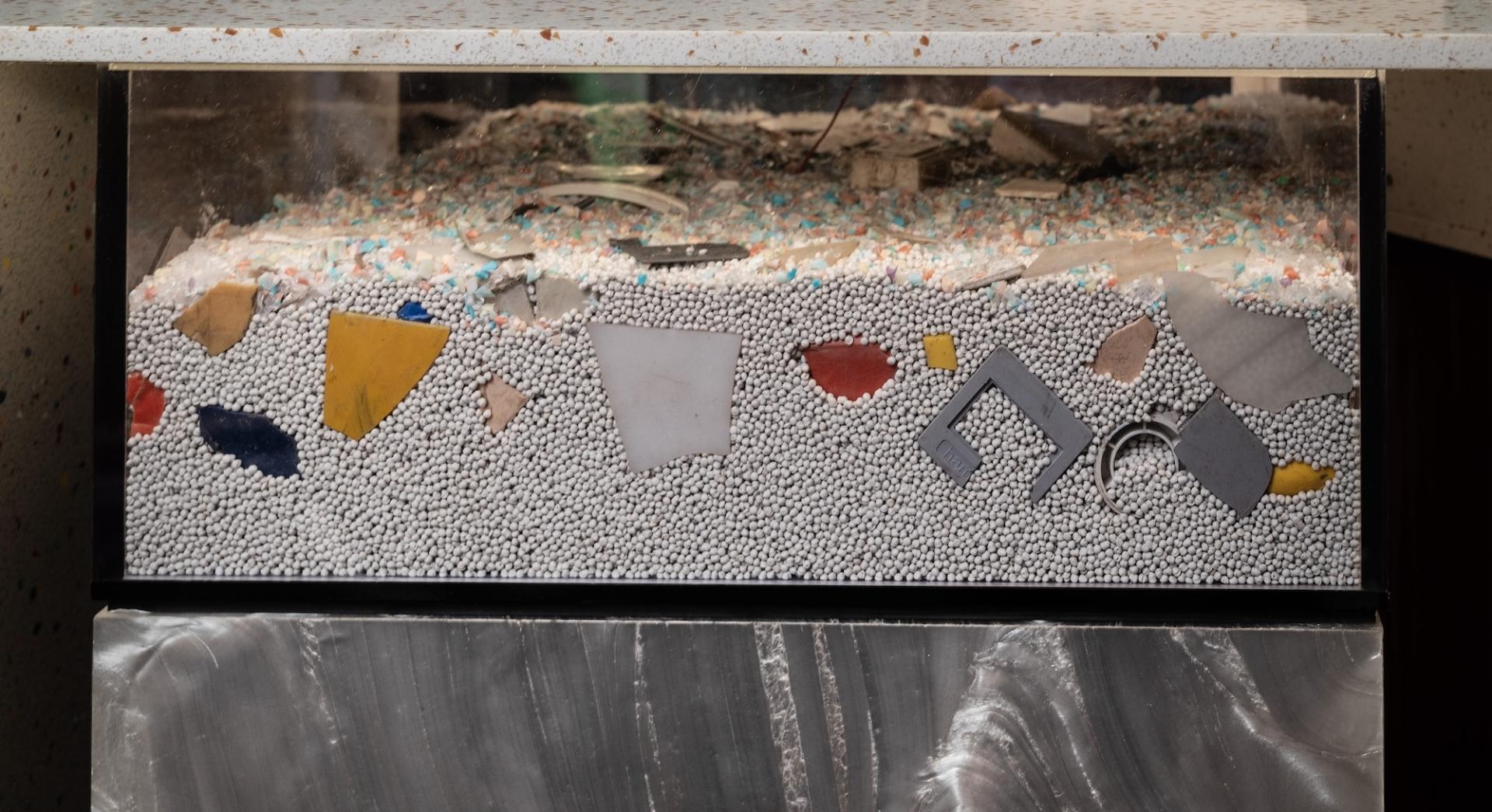 Colorful recycled materials and textured fragments displayed in a transparent container, representing Surface Matter's circular Material Rescue initiative.