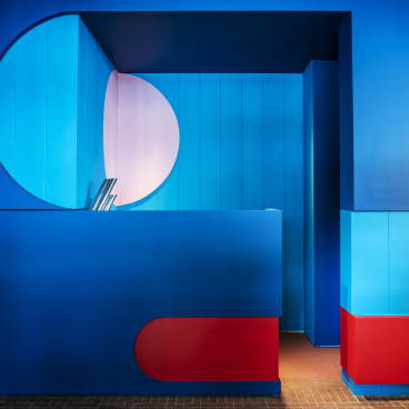 Vibrant reception area of The Standard, London, featuring bold blue and red geometric designs and modern architectural elements.