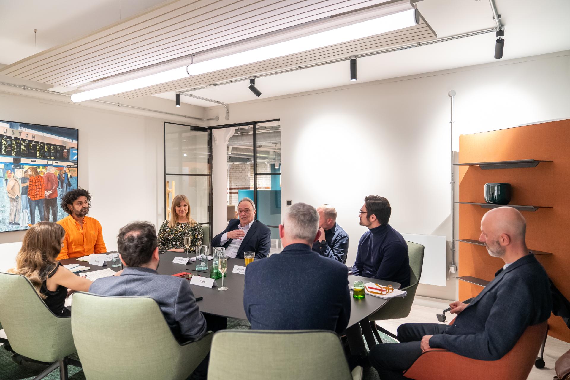 Diverse group of professionals discussing sustainability strategies during a seminar in a modern meeting room.