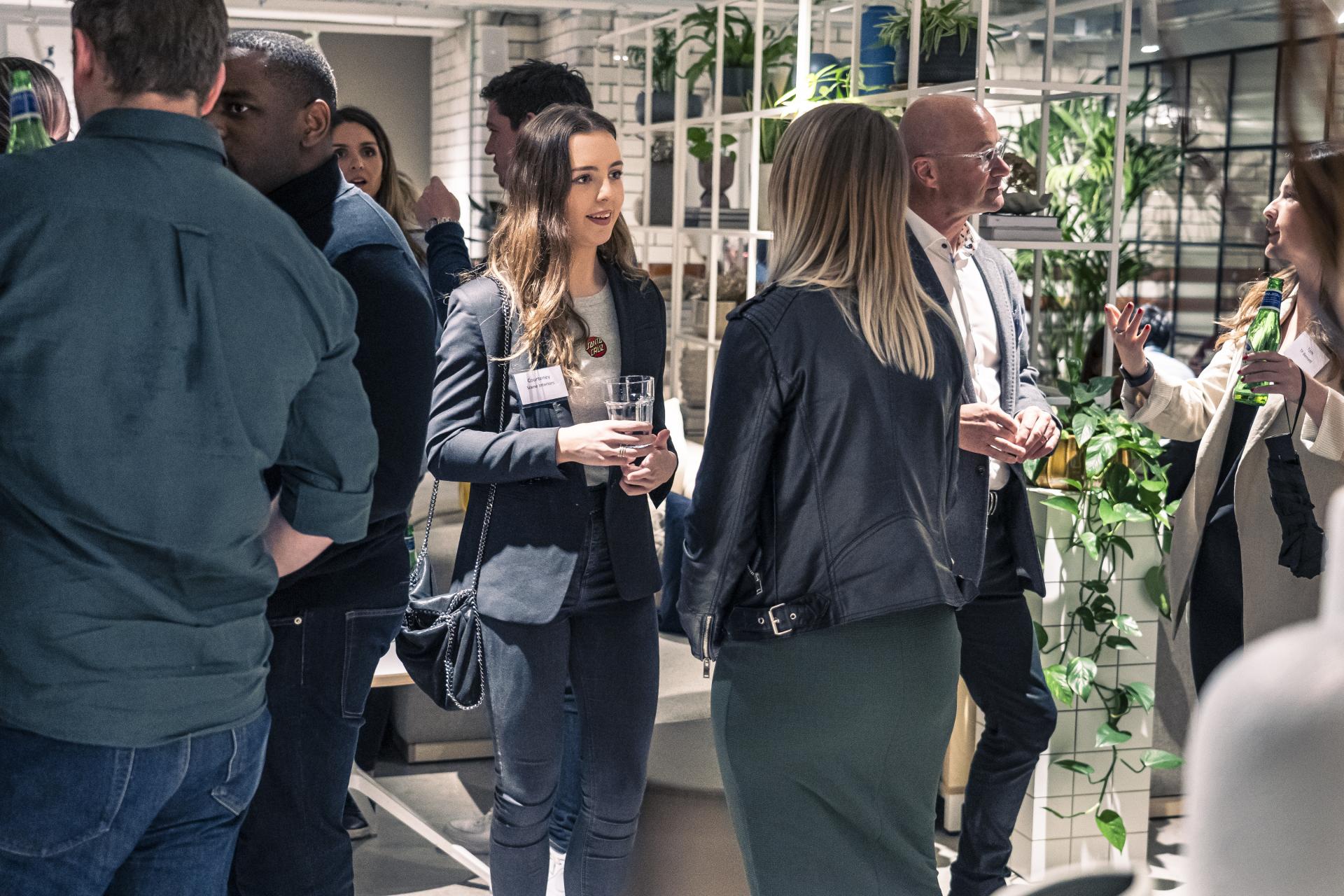 Networking event featuring diverse professionals discussing the future of residential design amidst greenery and modern decor.