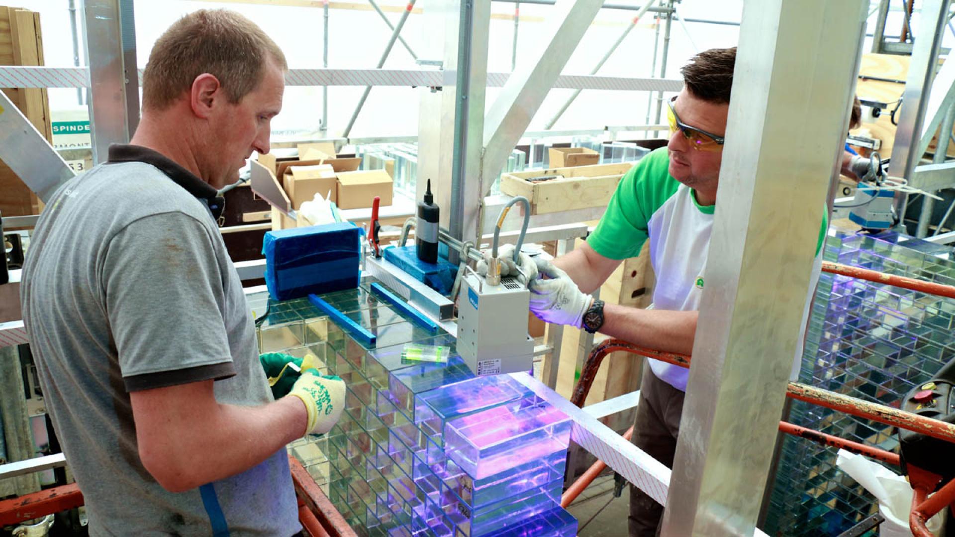 Two workers assembling glass blocks for the Crystal Houses façade project in Amsterdam, showcasing innovative architectural techniques.