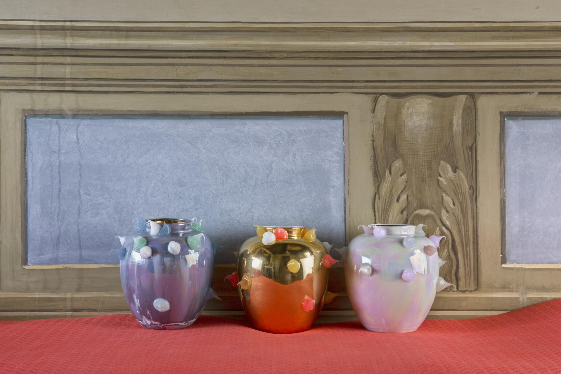 Colorful ceramic vases by Coralla Maiuri, featuring experimental designs and unique textures, displayed on a vibrant tabletop.