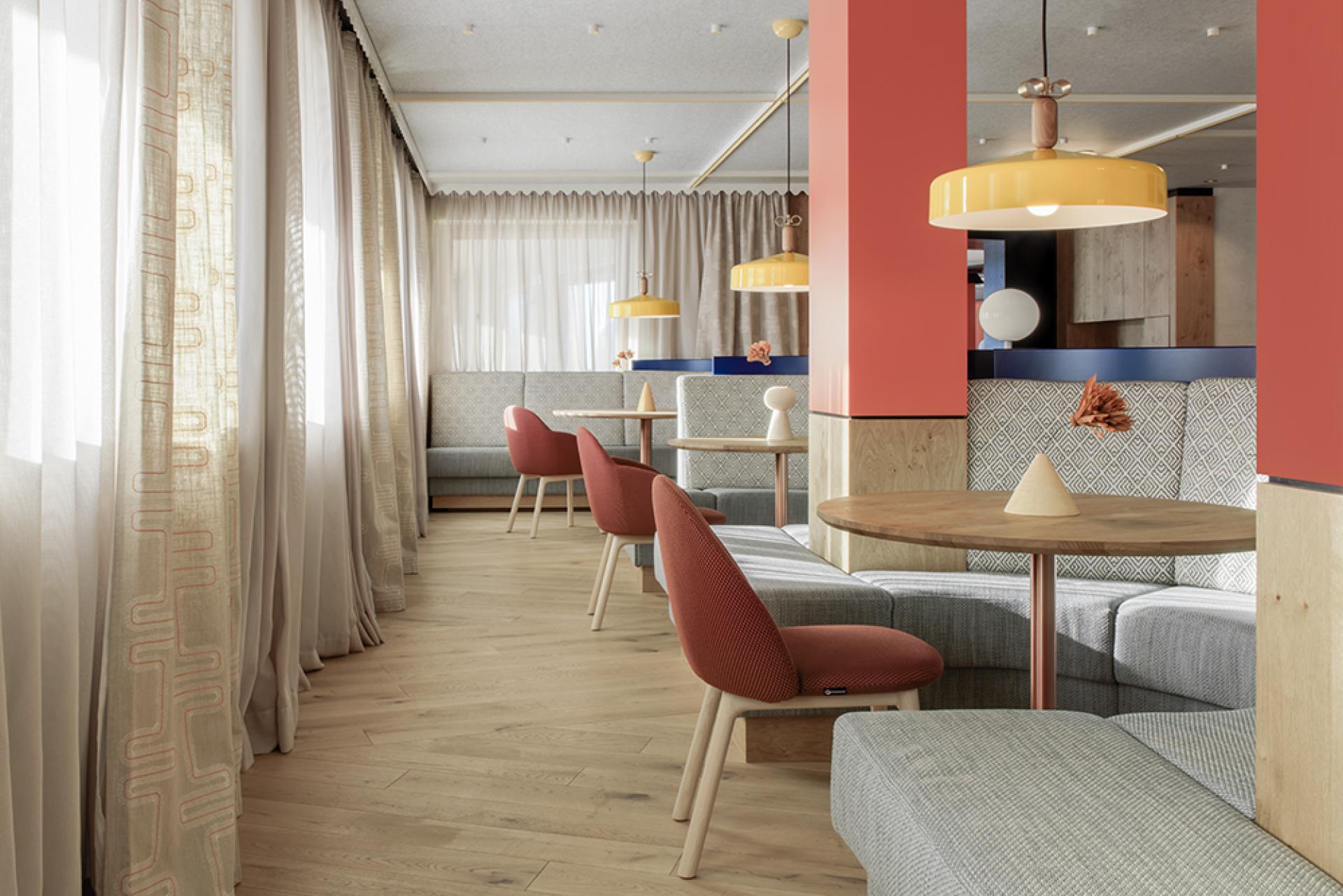 Stylish interior of Icaro Hotel featuring wooden elements, colorful lighting, and cozy seating with views of the Dolomites.