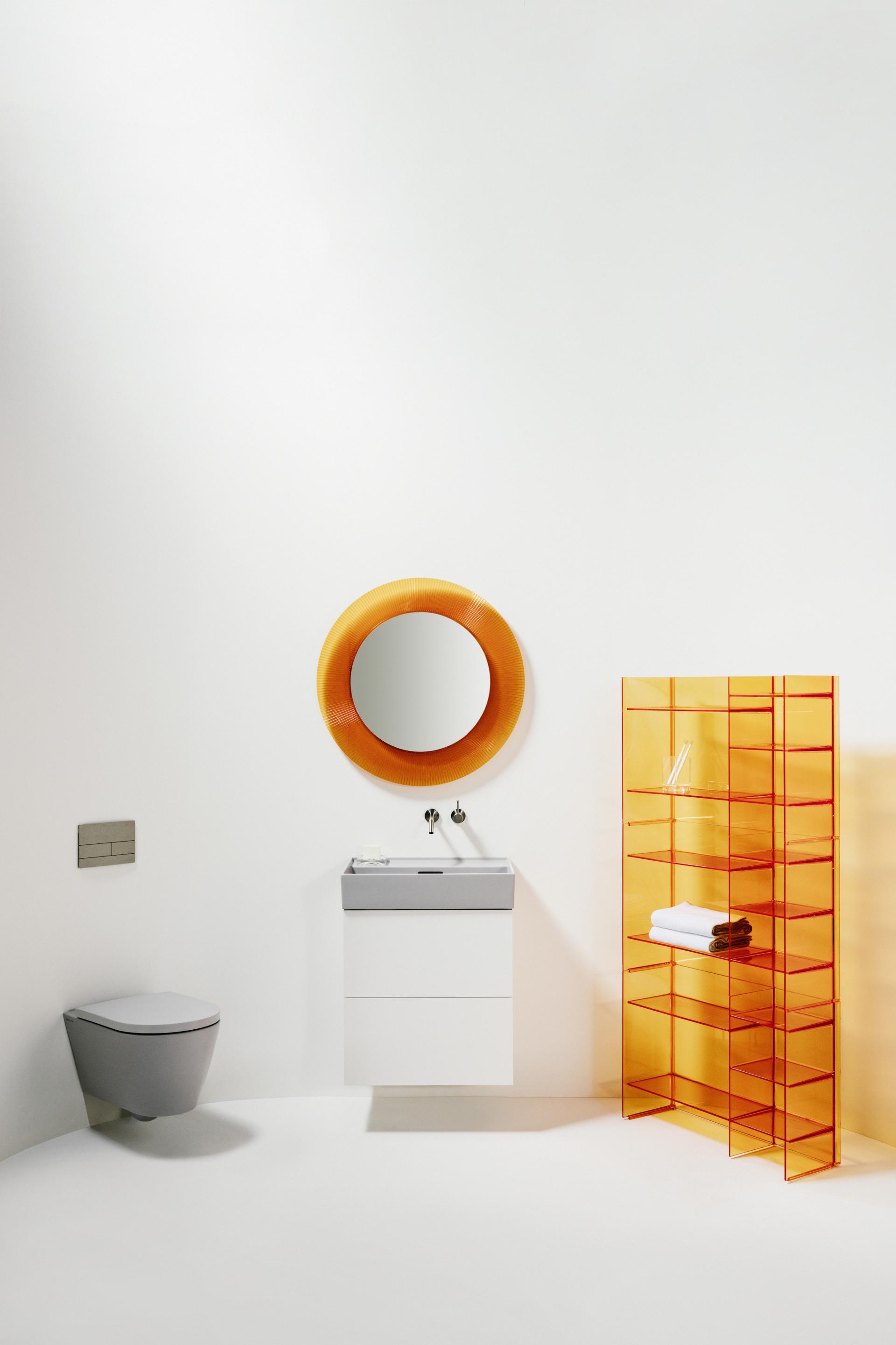 Modern bathroom featuring sleek Italian design elements, including an orange mirror and transparent storage unit by Kartell and Laufen.