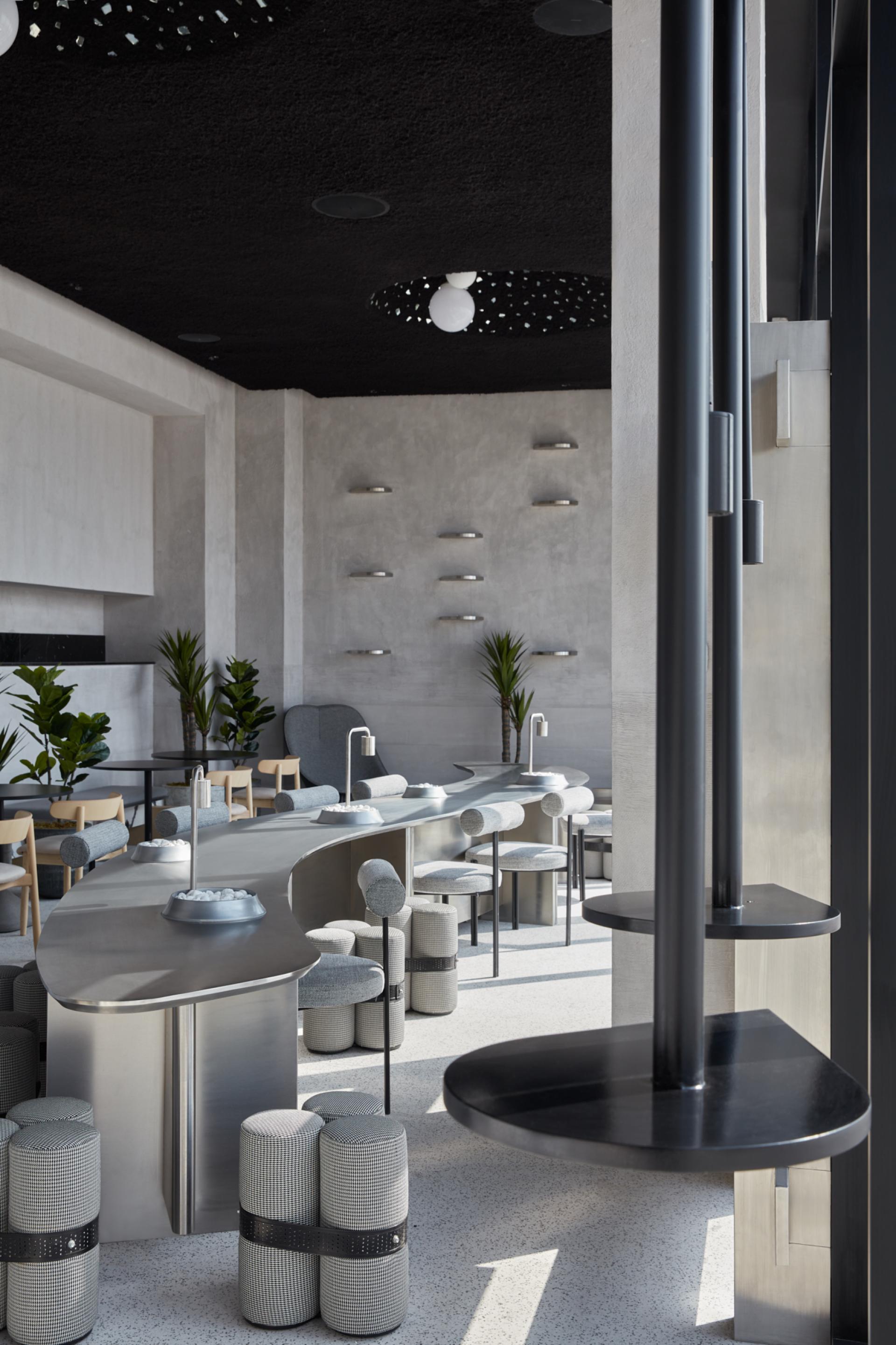 Minimalist coffee shop interior design featuring textured surfaces, unique seating, and a monochrome color palette in Abu Dhabi.