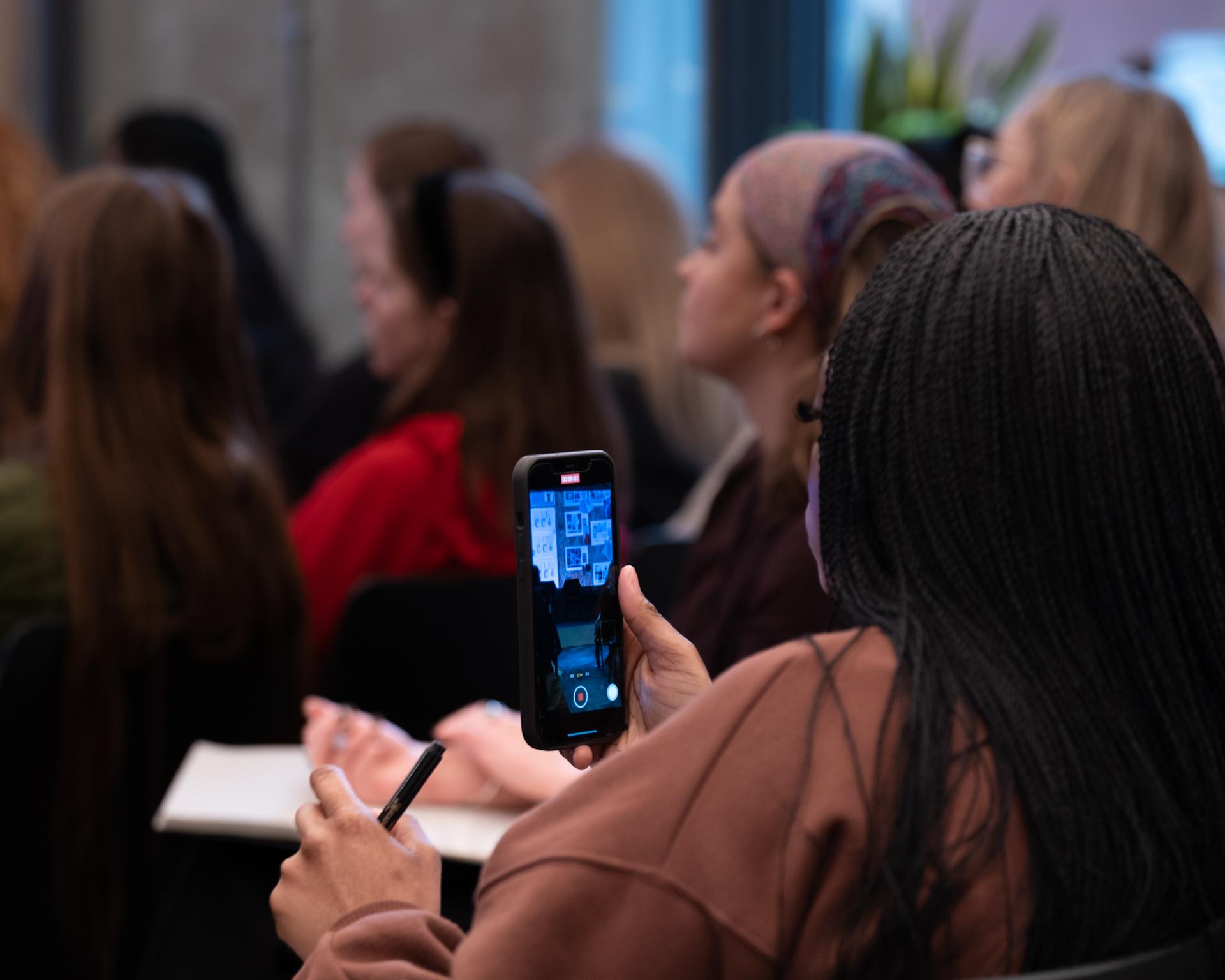 A participant using a smartphone to capture Laura Perryman's workshop on colour theory and nature's aesthetics.
