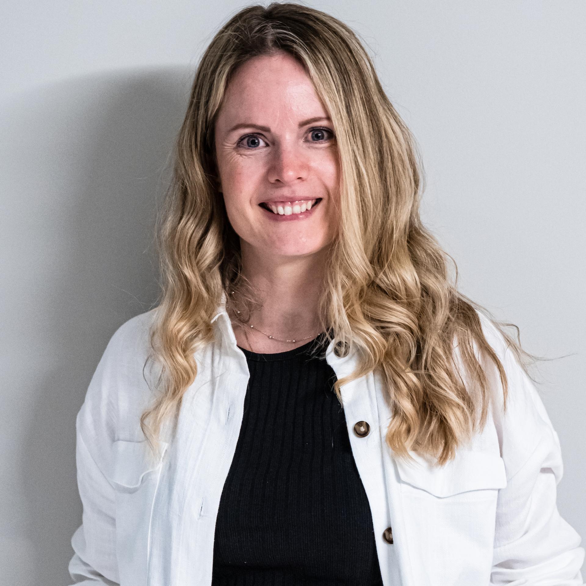 Smiling woman with long, wavy hair, promoting co-living and property insights at a Manchester seminar.