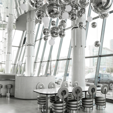 Modern interior of MO bakehouse in Khobar, featuring stylish round tables and unique metallic decor.