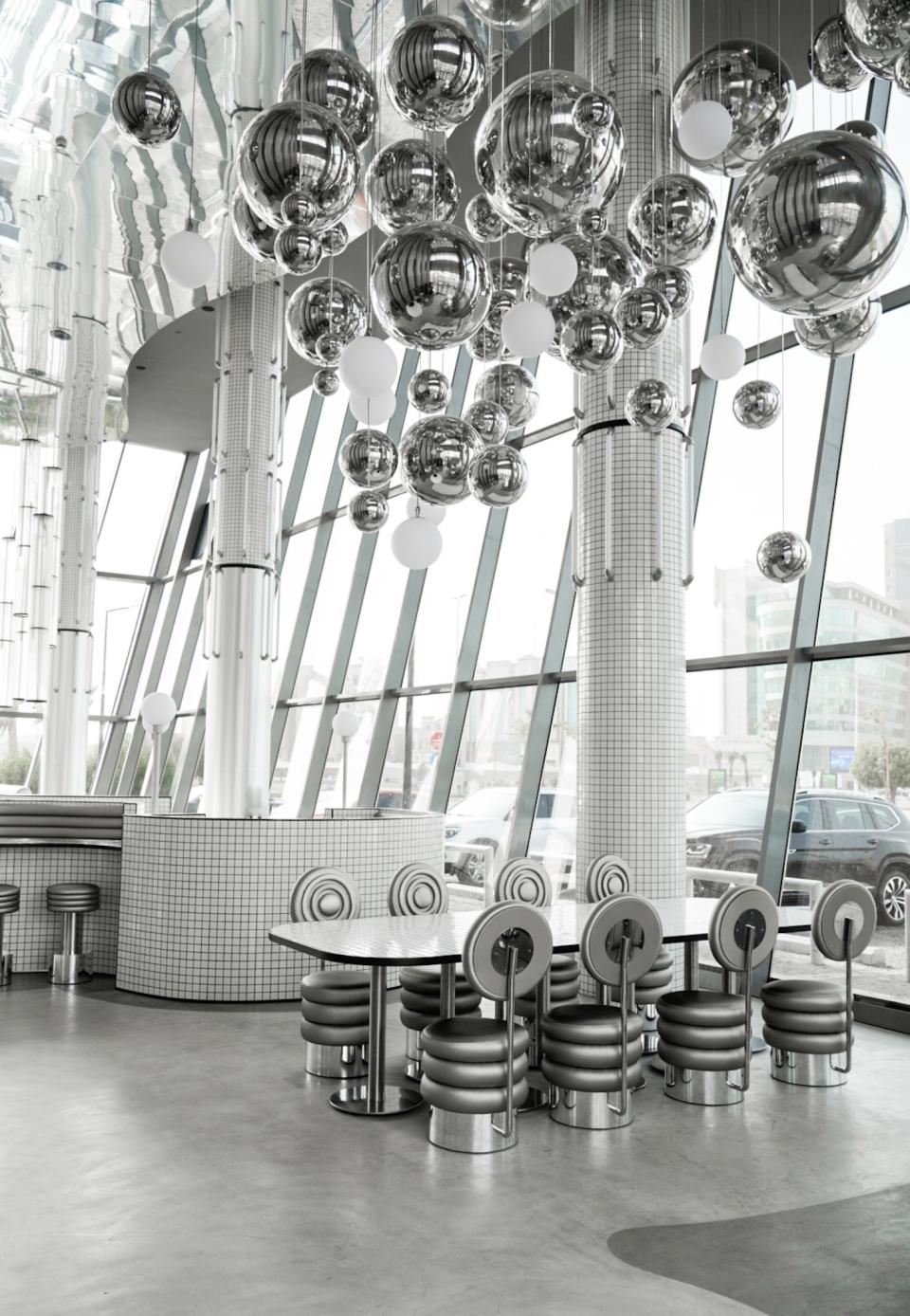 Modern interior of MO bakehouse in Khobar, featuring stylish round tables and unique metallic decor.