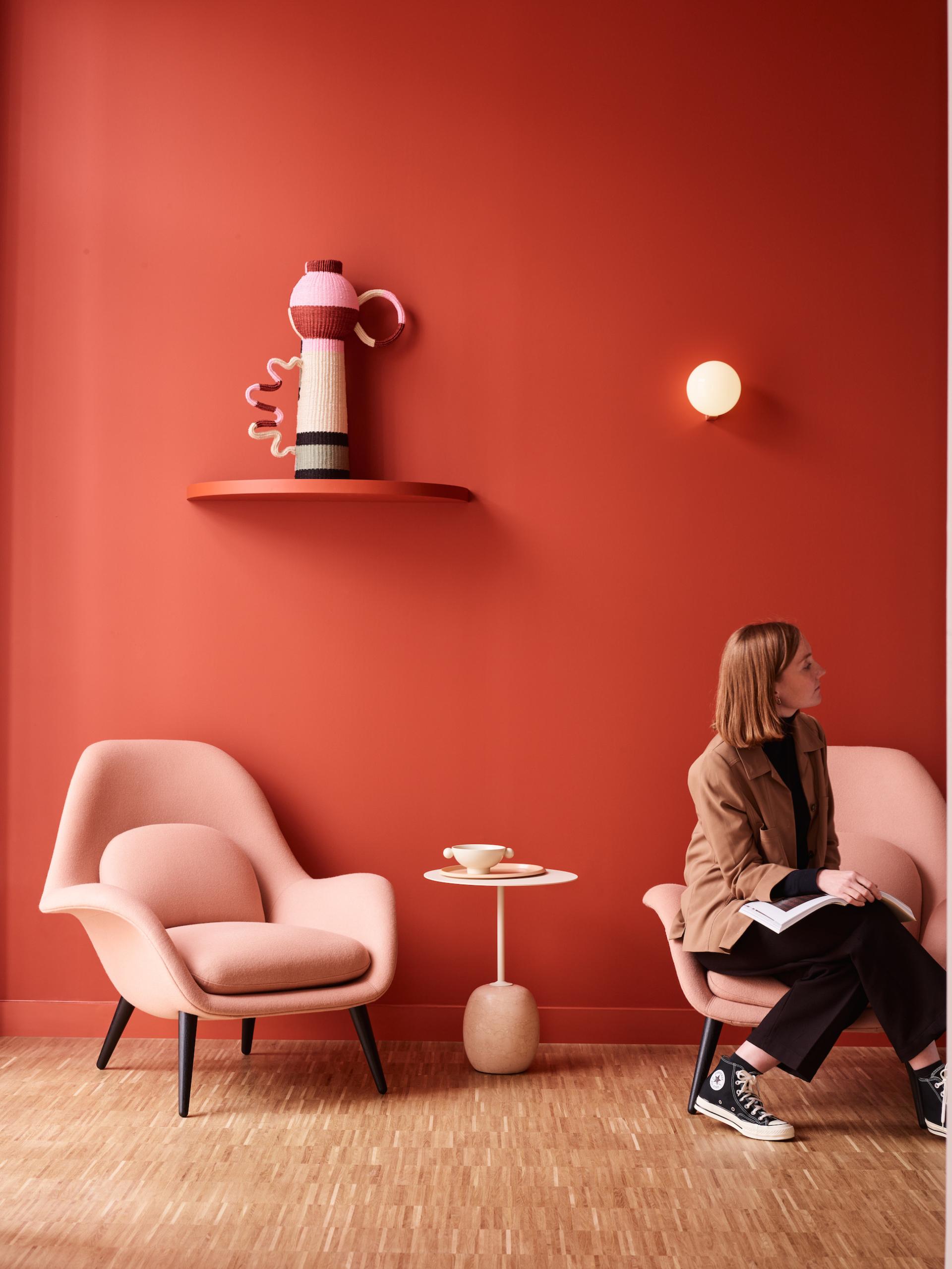 A stylish workspace featuring coral walls, modern seating, and a decorative sculpture, embodying Liberty House's unique design aesthetic.