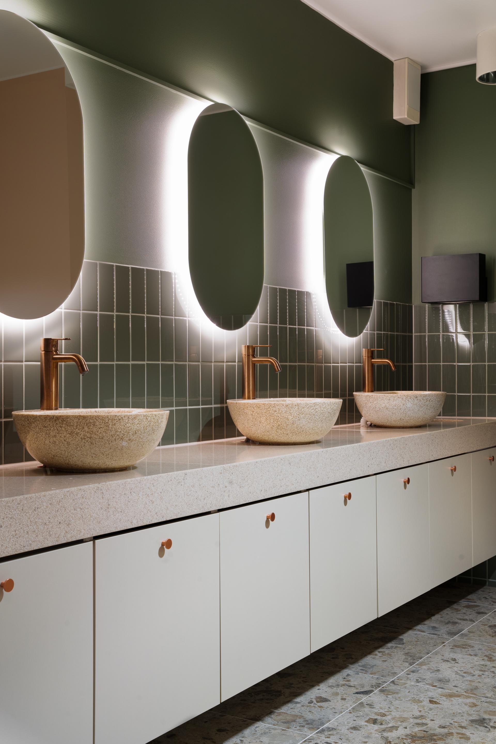 Stylish bathroom design featuring elegant stone sinks, modern lighting, and sleek cabinetry in a Material Source Studio setting.
